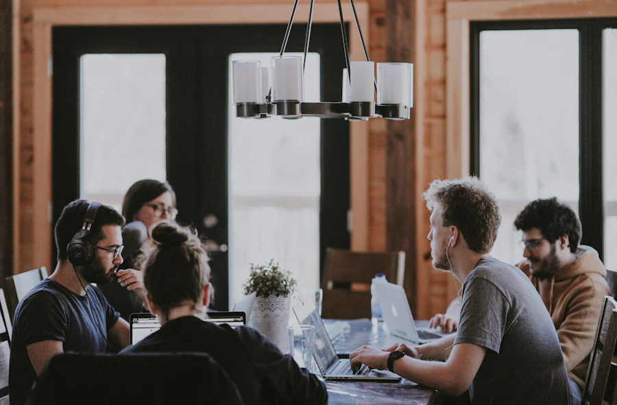 Equipe reunida em torno de uma mesa analisando telas e anotações de um projeto